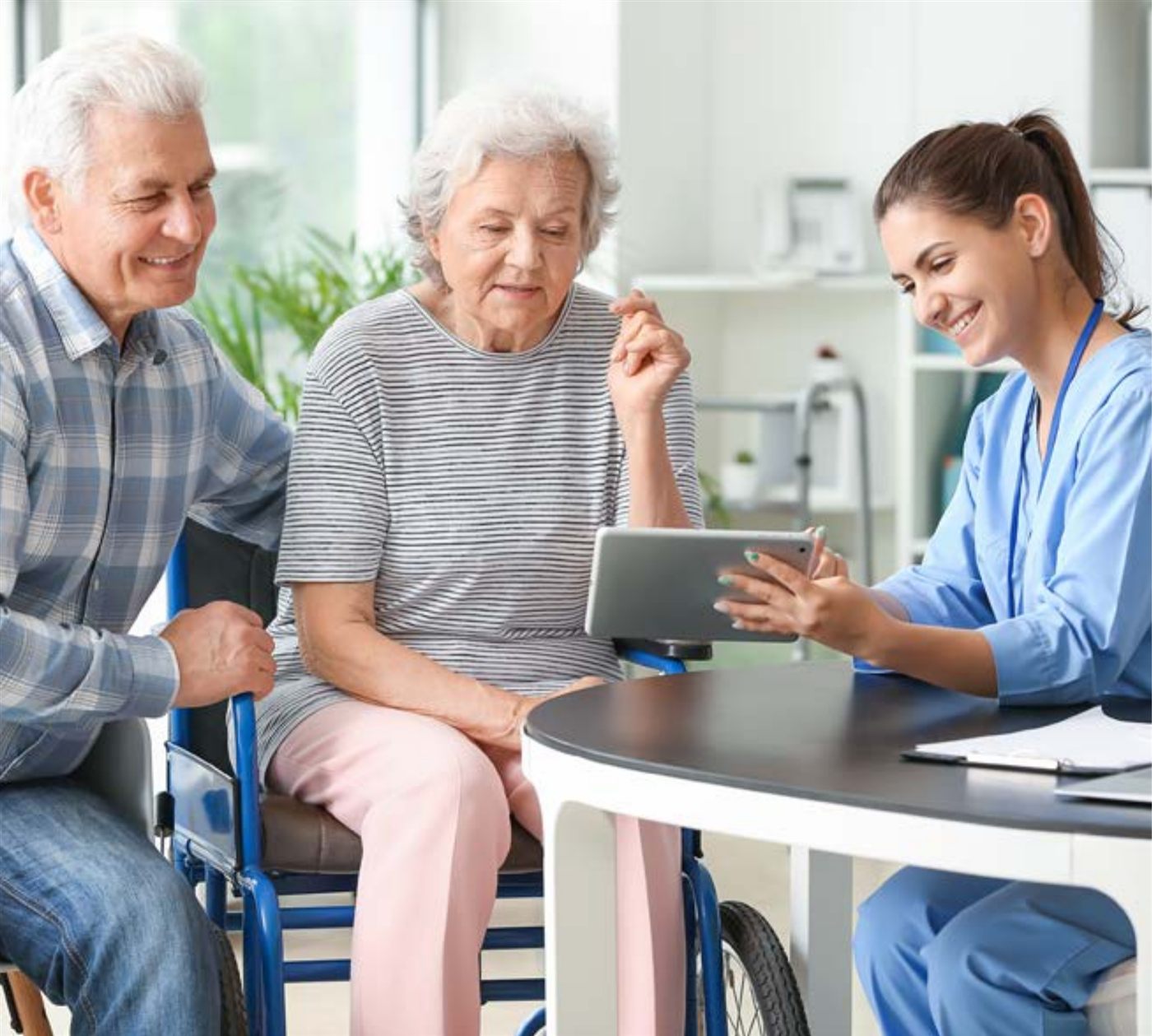 Ältere Menschen mit Pflegekraft und Tablet-Steuerung